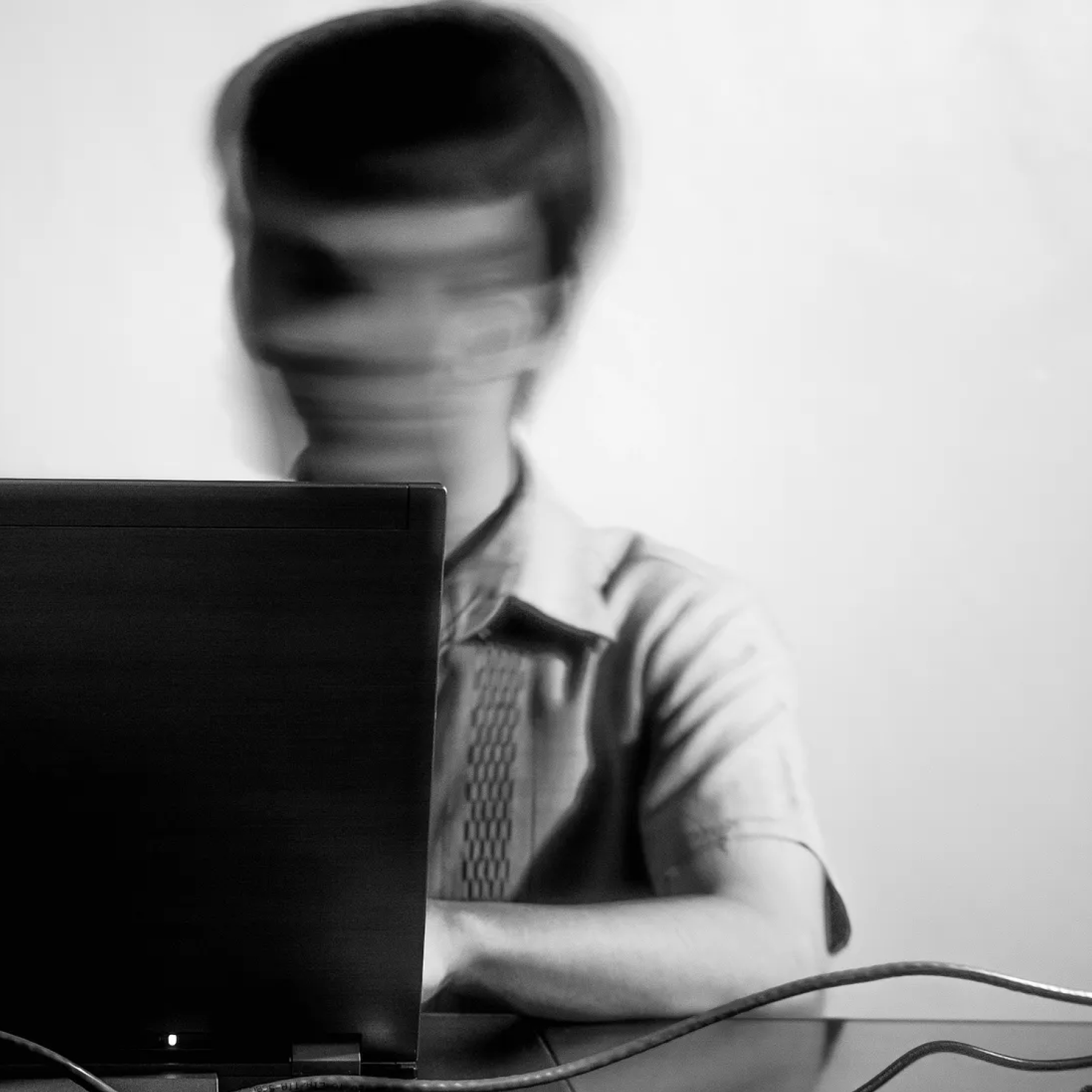 photo of a person using a computer and moving their head rapidly creating a blurry image of their face