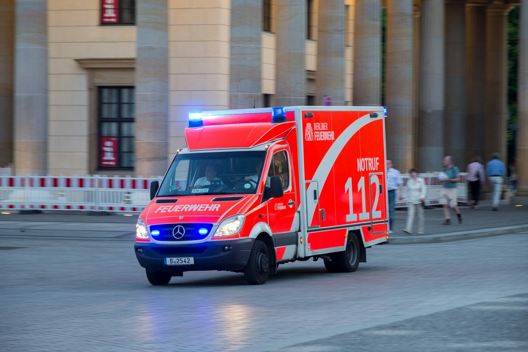 Ein Rettungswagen fährt mit eingeschaltetem Blaulicht auf einer Straße.