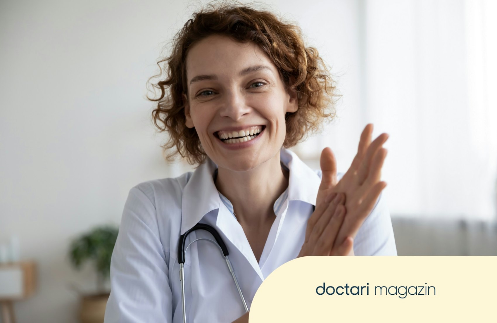 Breit lächelnde junge Ärztin im Kittel mit Stethoskop