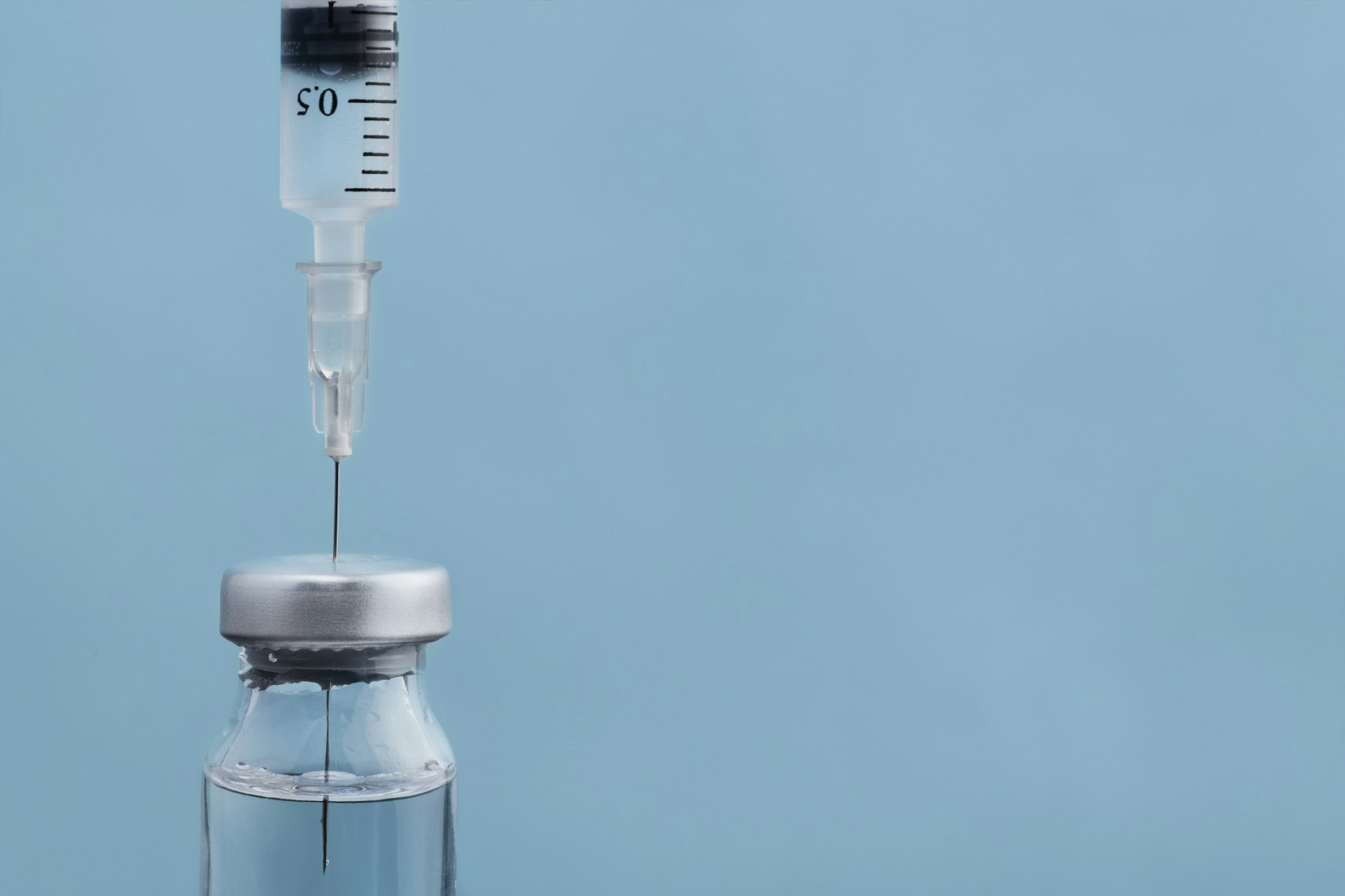 Spritze steckt mit der Nadel in einer Ampulle mit Impfstoff