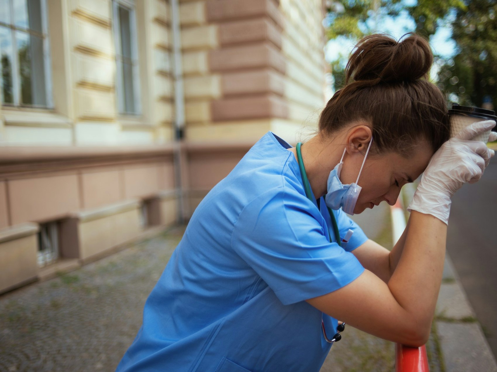 Eine müde Krankenschwester stützt ihren Kopf auf ihre Hände