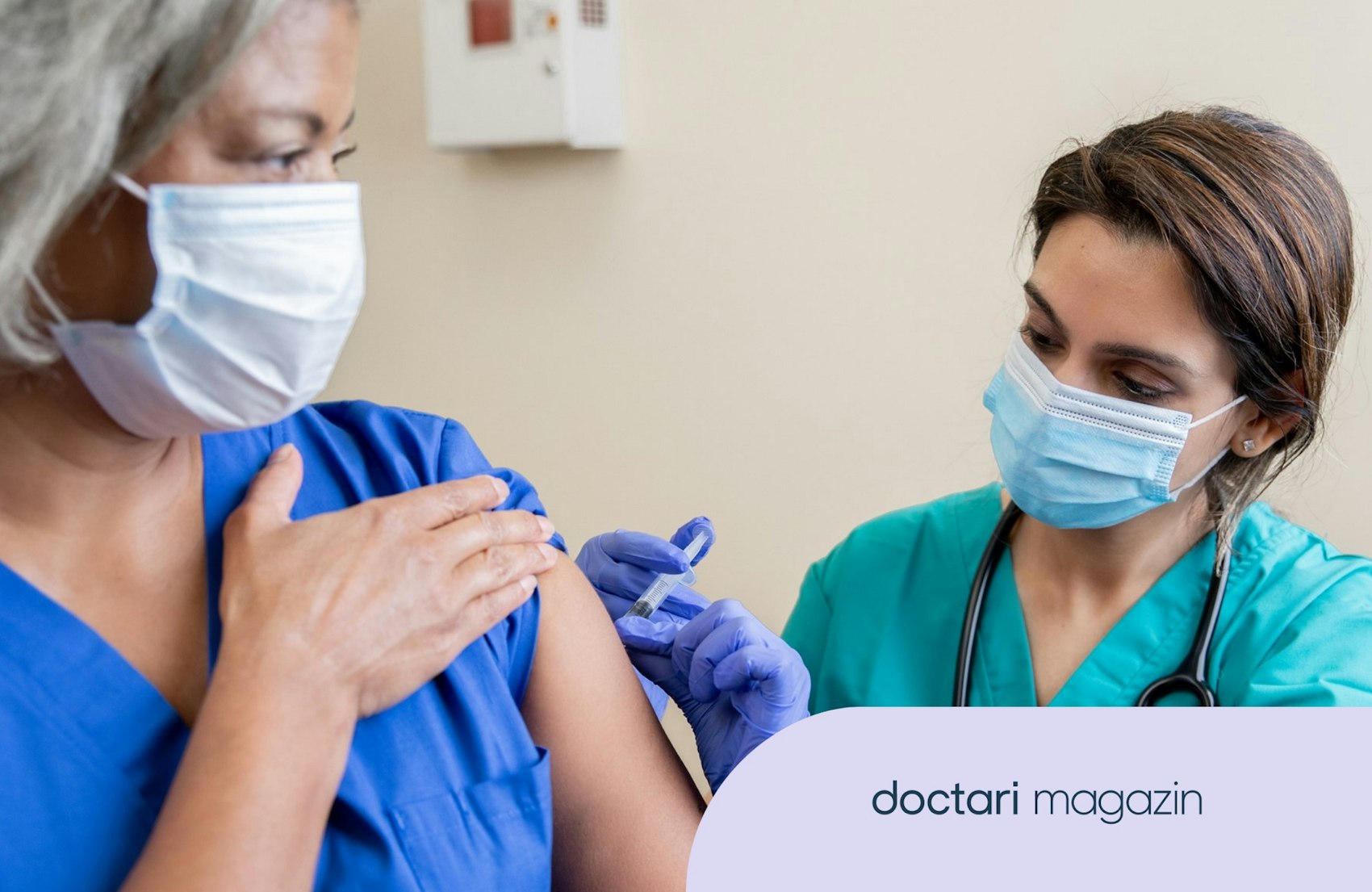 Junge Ärztin impft eine Pflegefachkraft. Beide tragen einen Mundschutz.