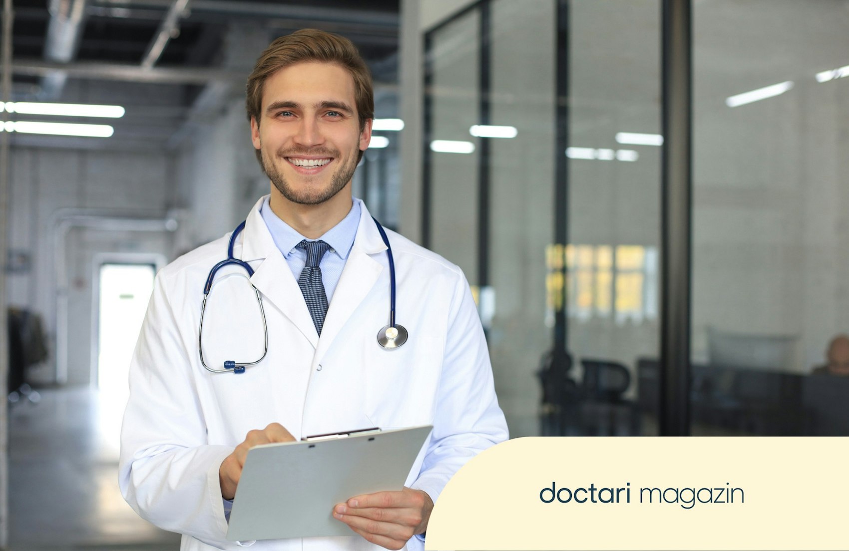 Junger Arzt mit Klemmbrett in der Hand lächelt in die Kamera.