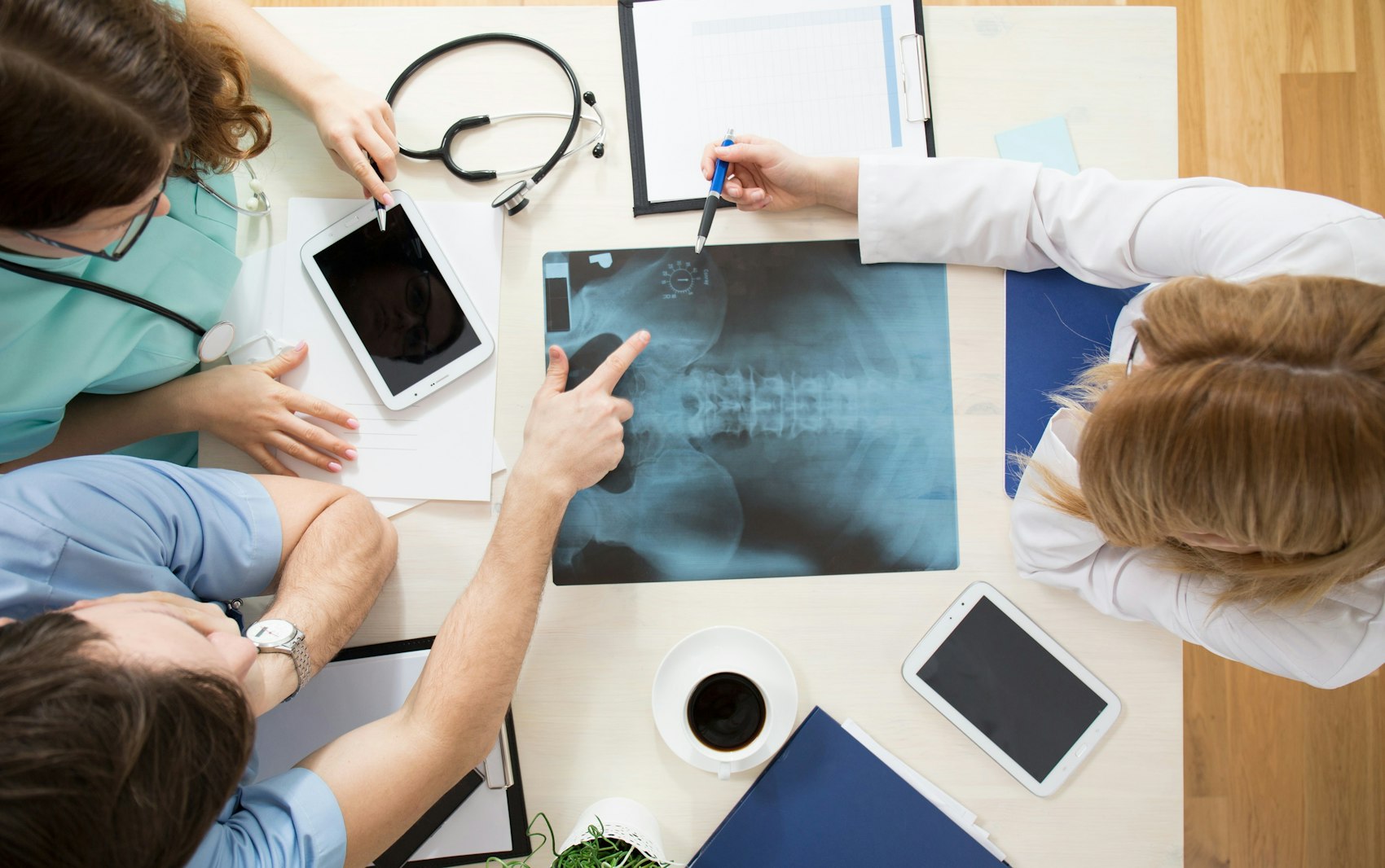 Drei Mediziner sitzen an einem Tisch und betrachten gemeinsam ein Röntgenbild