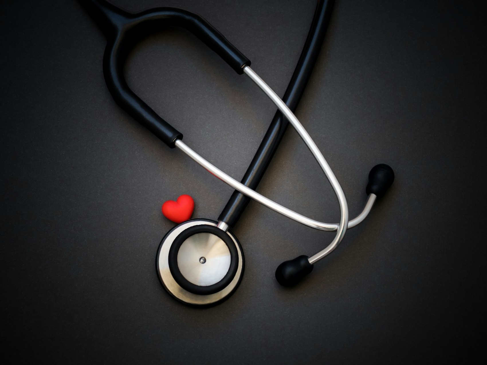 Ein Stethoskop und ein rotes Herz liegen auf einem Tisch.