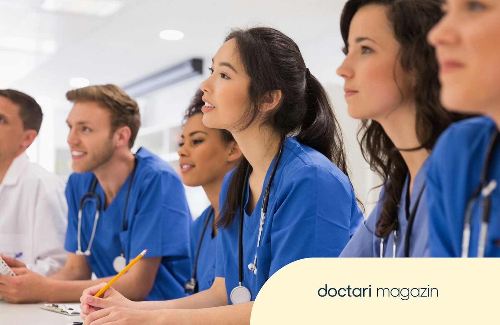 Medizinstudenten und Medizinstudentinnen sitzen während einer Vorlesung an einem Schreibtisch.