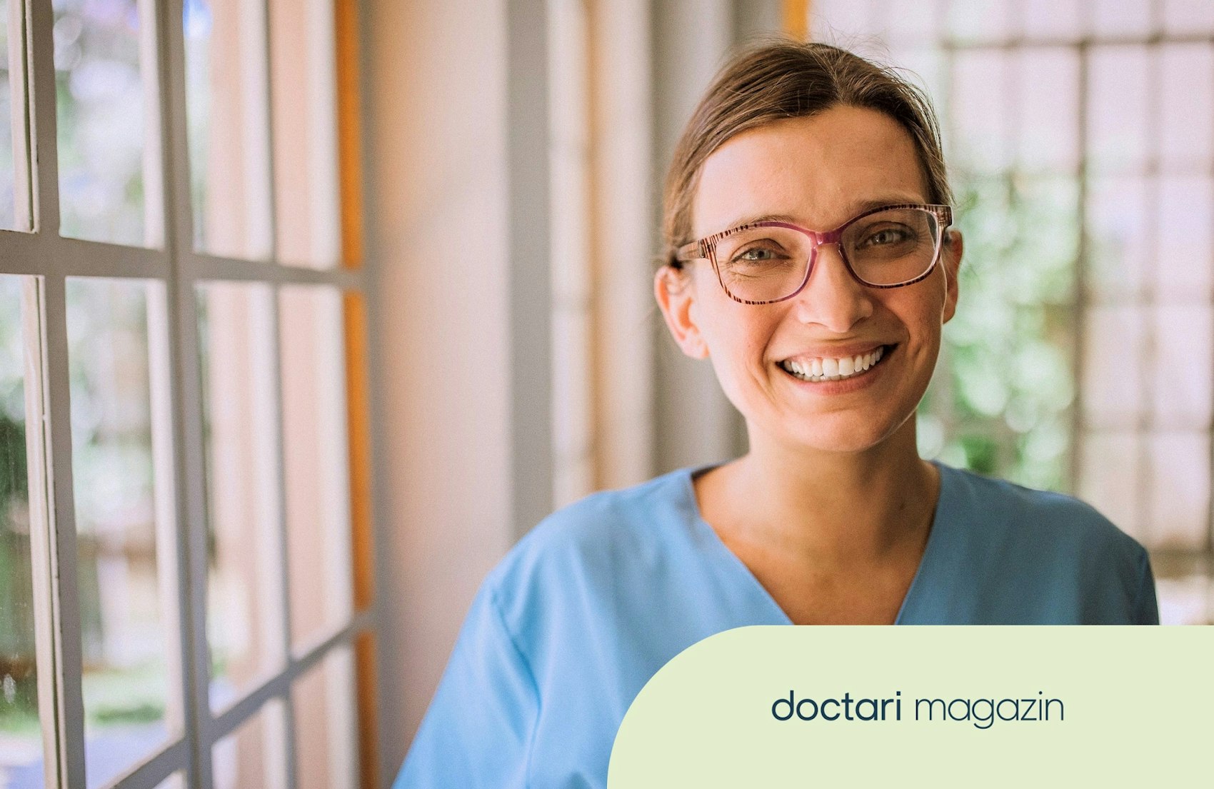 Junge Pflegerin mit Brille lächelt in die Kamera
