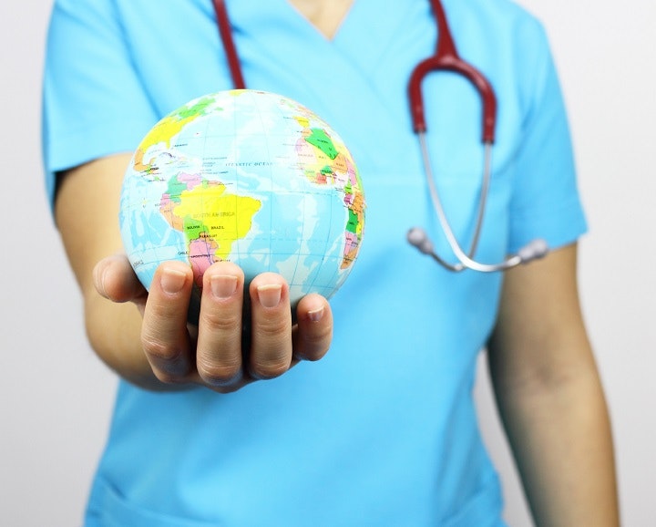 Eine Klinikmitarbeiterin hält symbolisch eine kleine Weltkugel in Händen. 