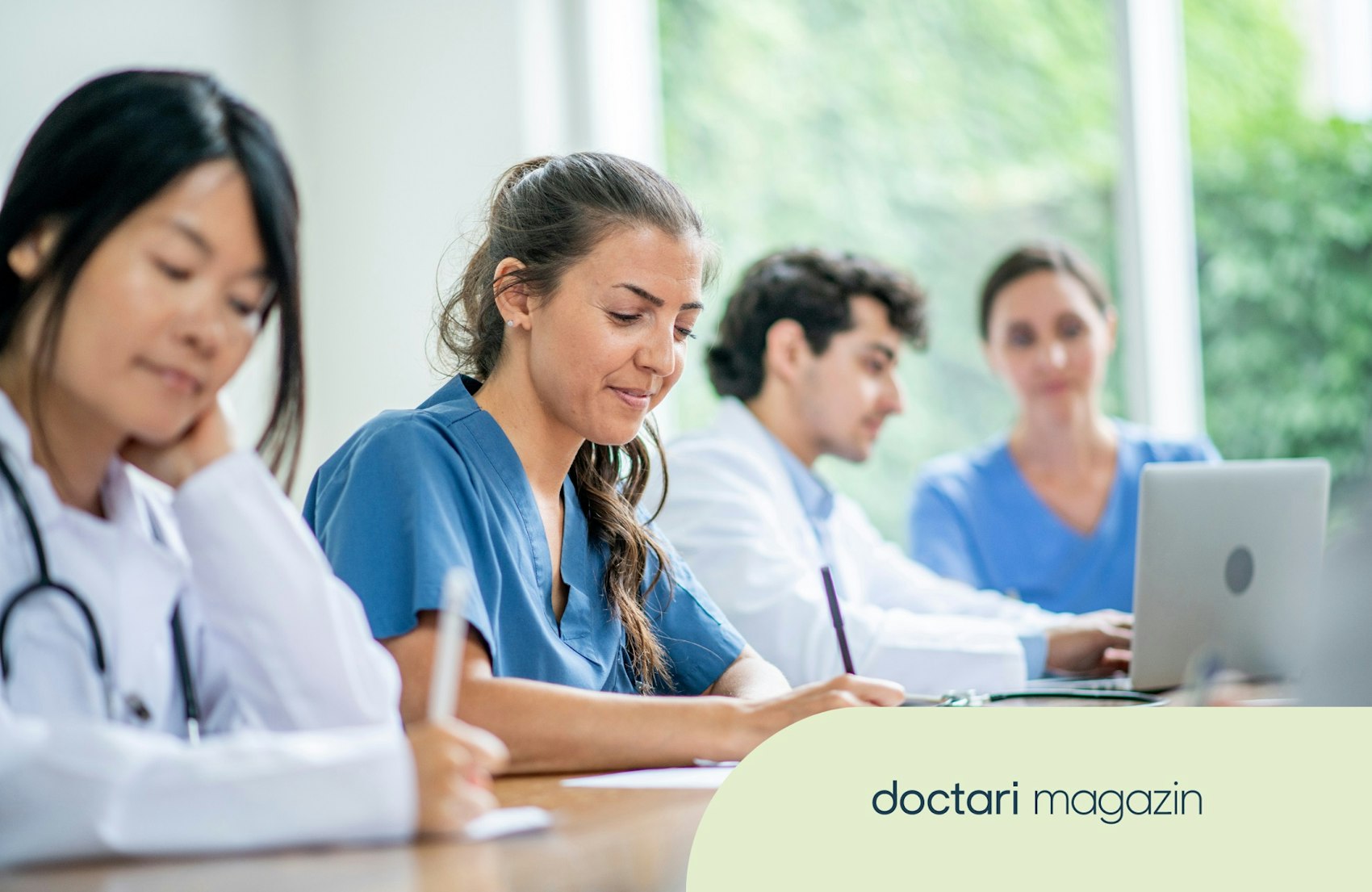 Junge Pflegestudierende sitzen an Tischen und schreiben.