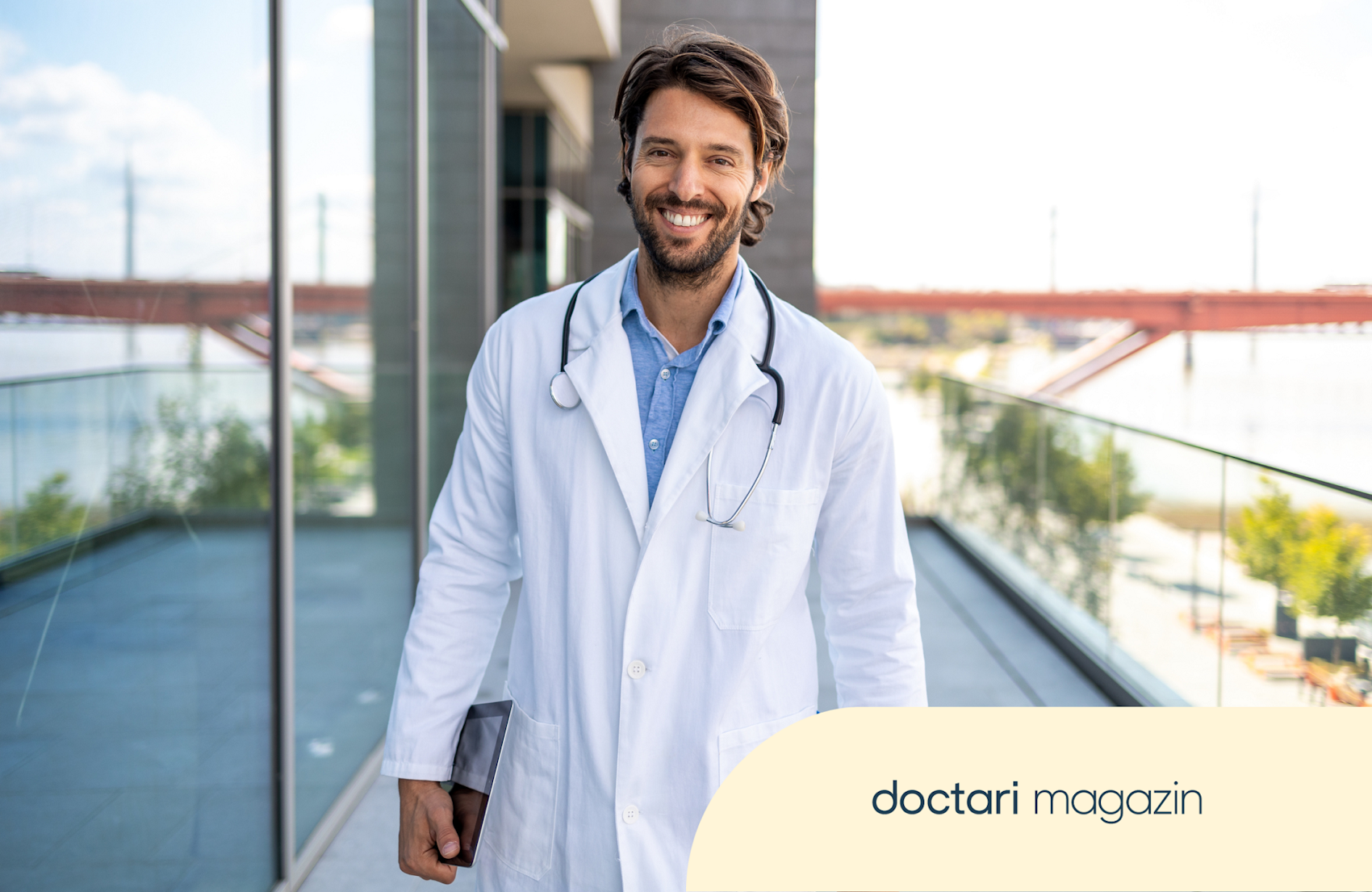 Junger Arzt im Kittel steht auf dem Balkon eines Krankenhauses.