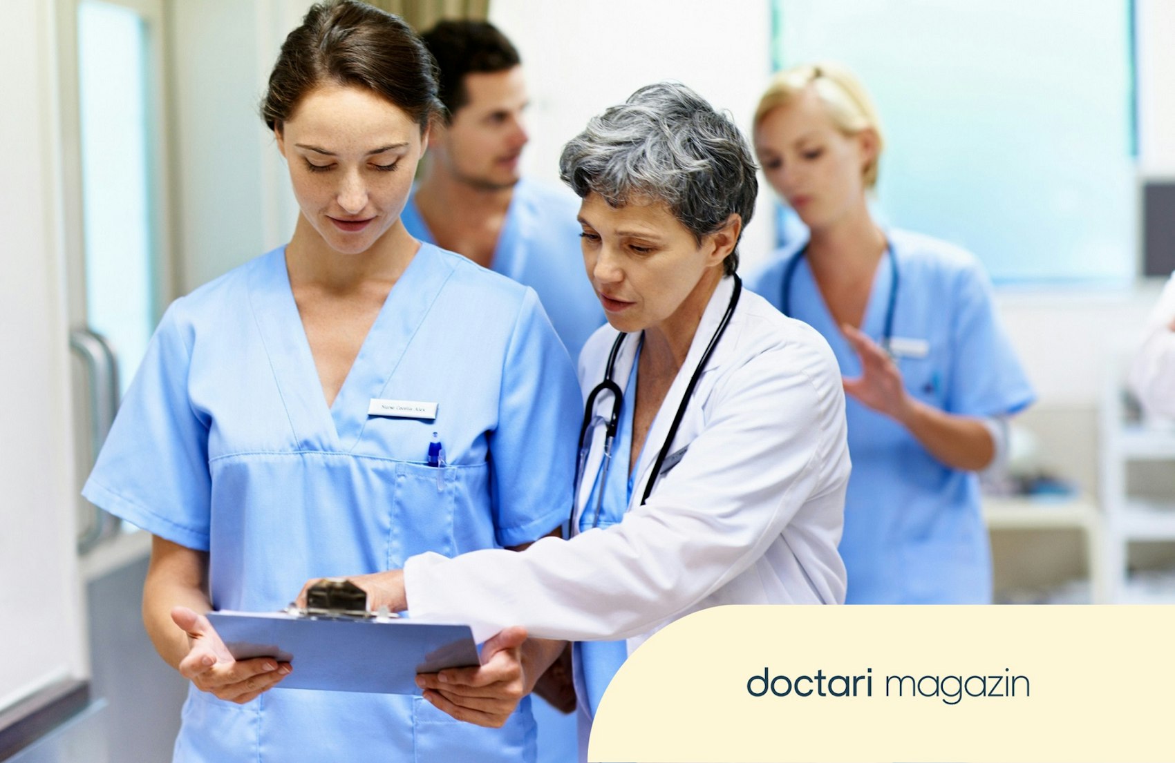 Ältere Oberärztin blickt gemeinsam mit junger Ärztin auf ein Klemmbrett.