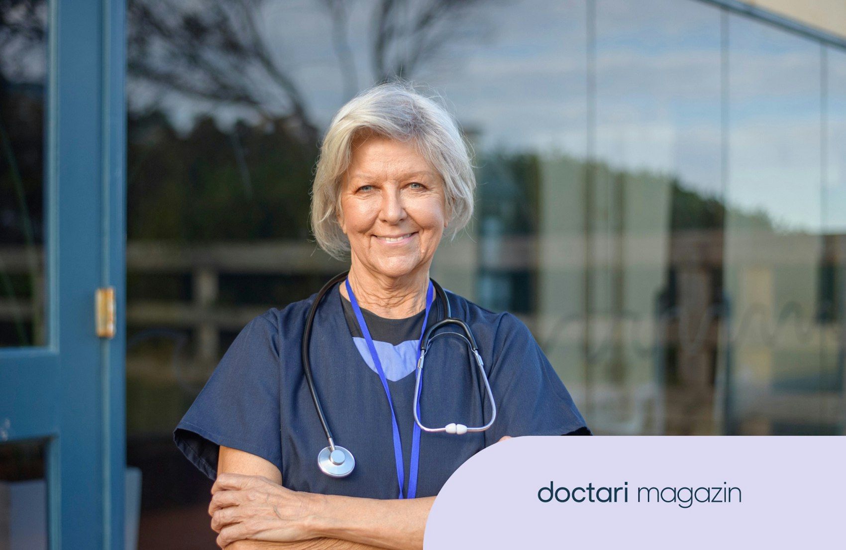 Eine ältere Pflegekraft mit grauen Haaren lächelt in die Kamera