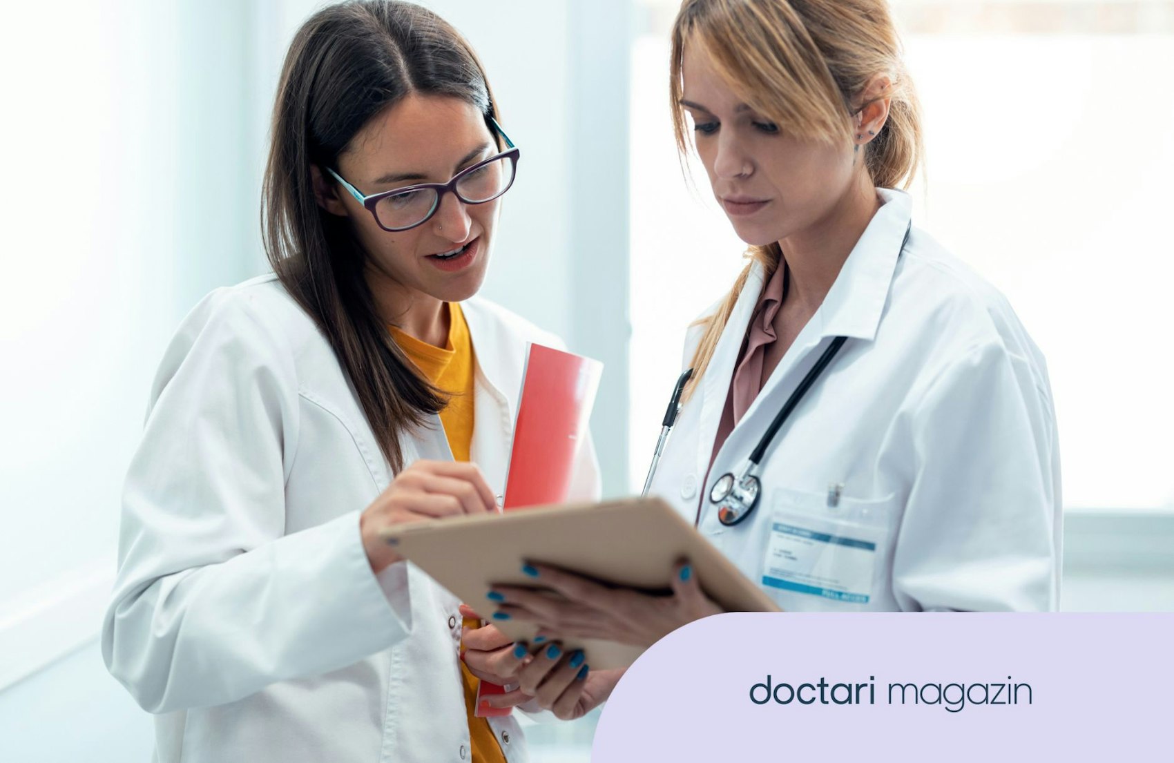 Zwei Ärztinnen blicken auf ein Klemmbrett und tauschen sich aus