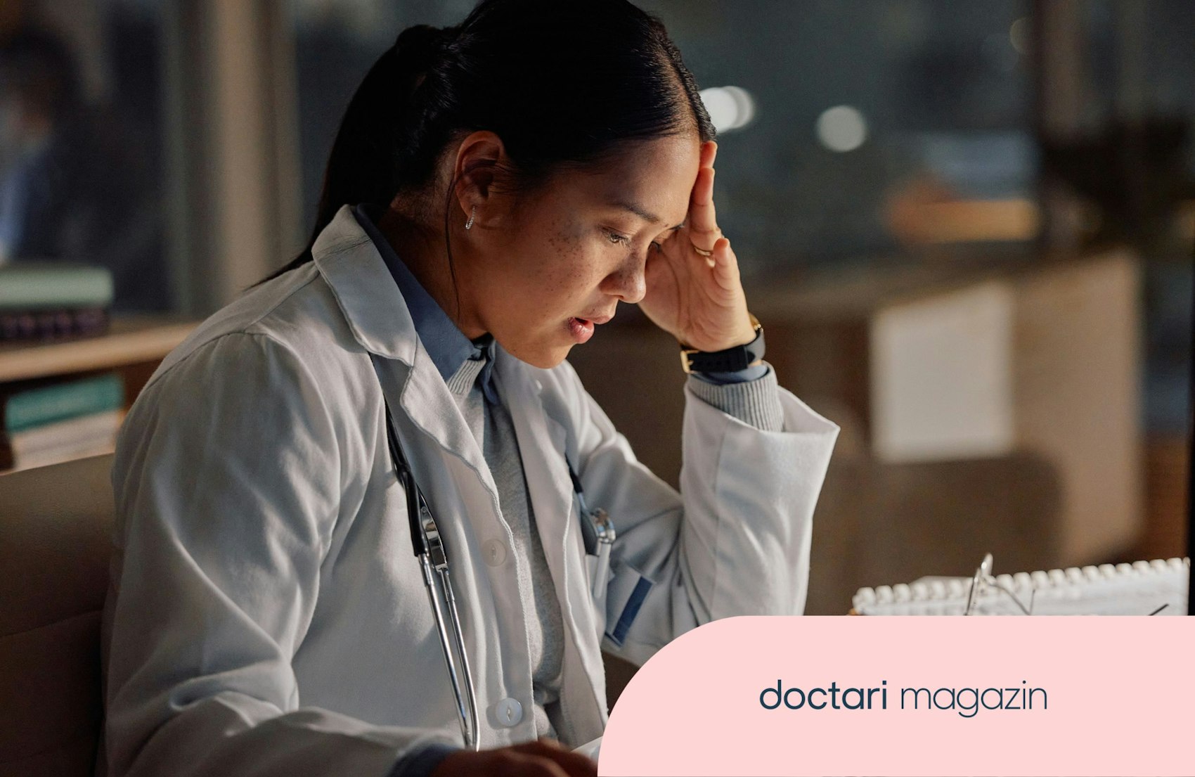 Eine Ärztin sitzt im dunklen Raum am Schreibtisch