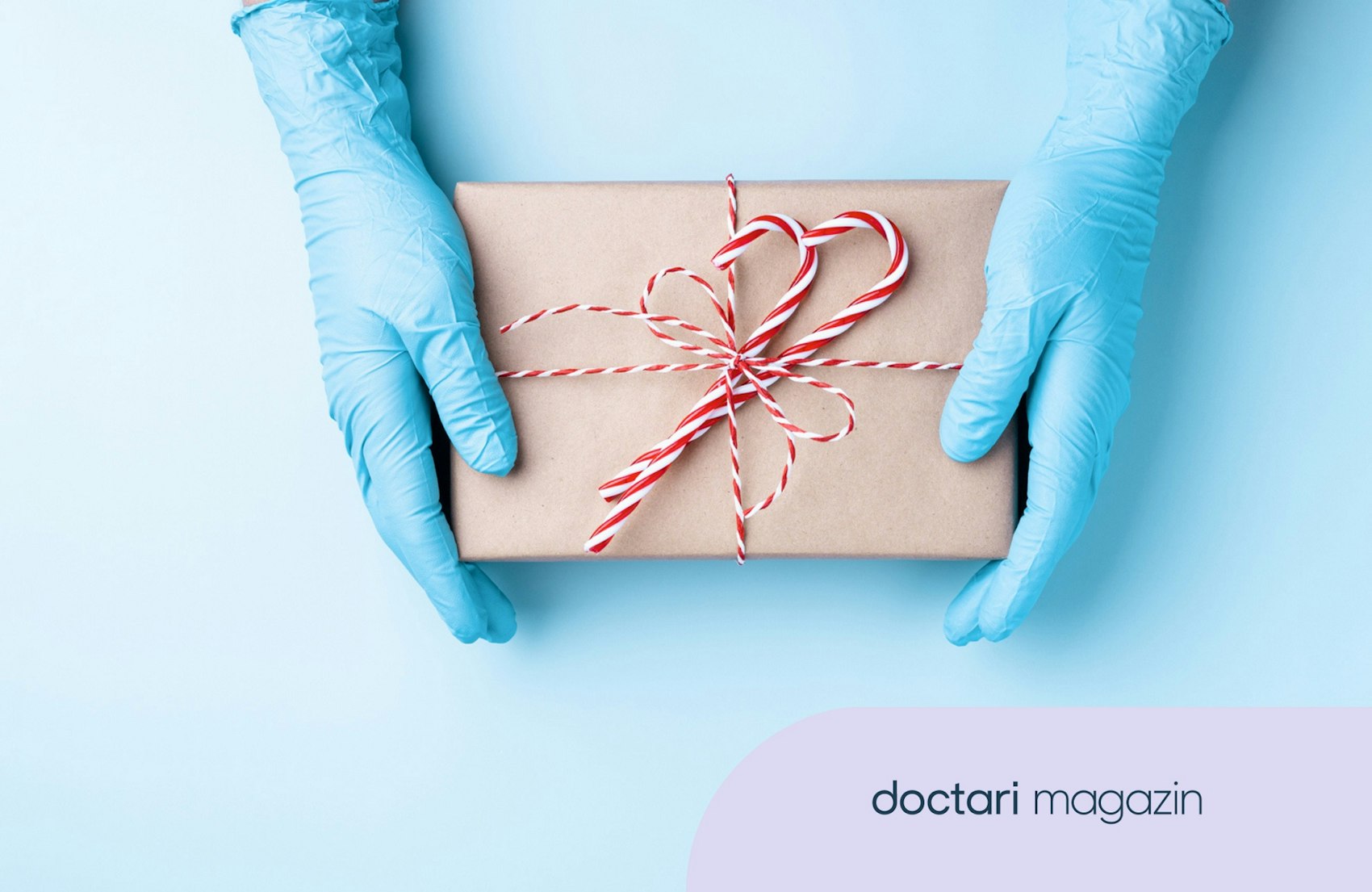Zwei Hände, die blaue Einweghandschuhe tragen, halten ein Geschenk.