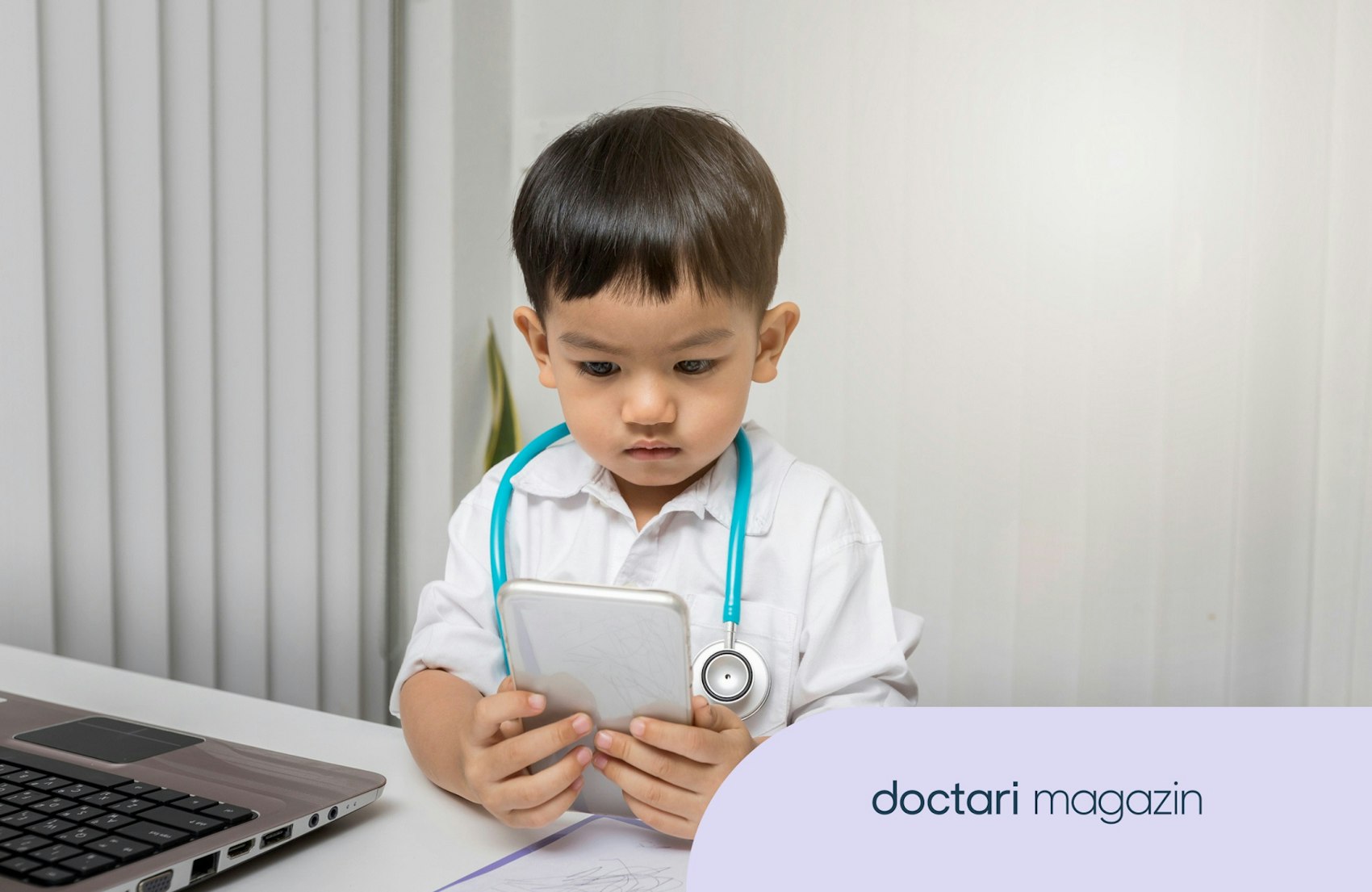 Ein kleiner Junge mit Stethoskop um den Hals blickt auf ein großes Smartphone.