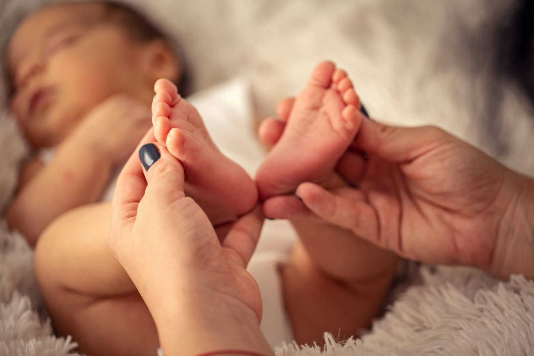 Zwei Hände halten die Füße eines Säuglings
