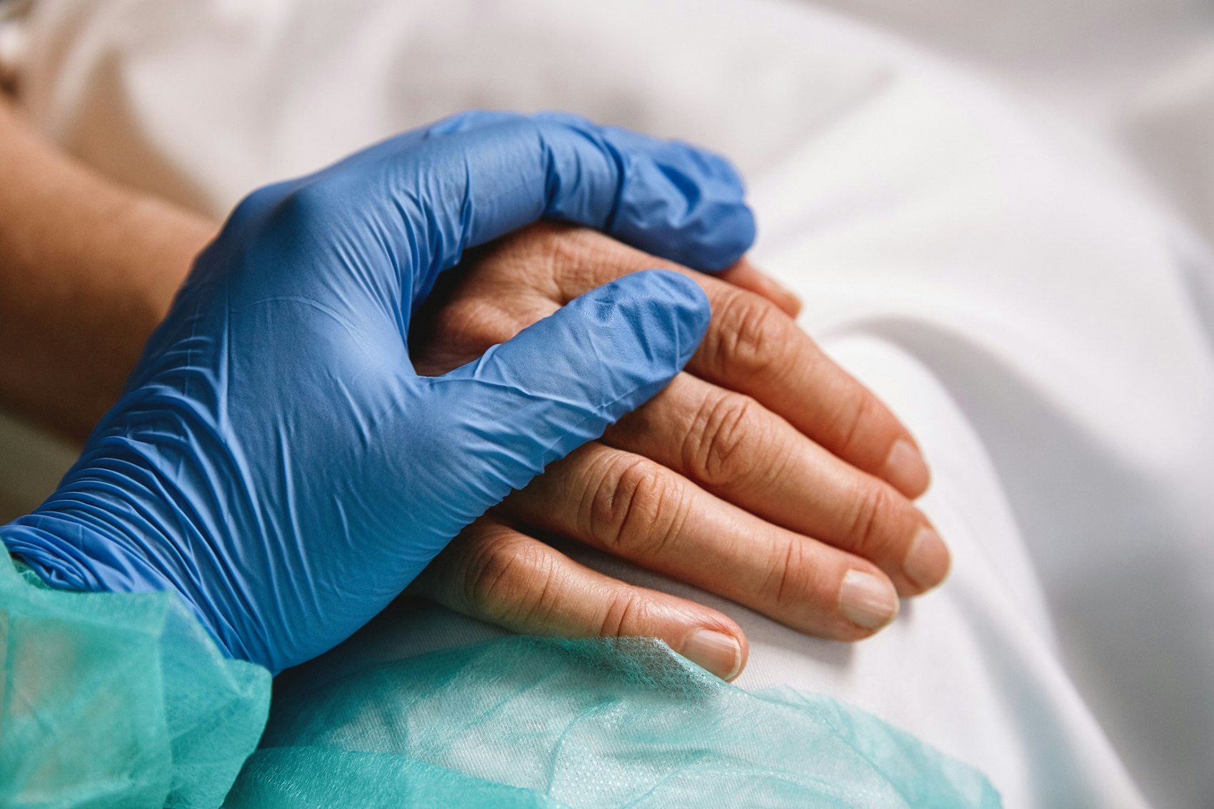 Die Hand einer medizinischen Fachkraft liegt auf der eines Patienten.