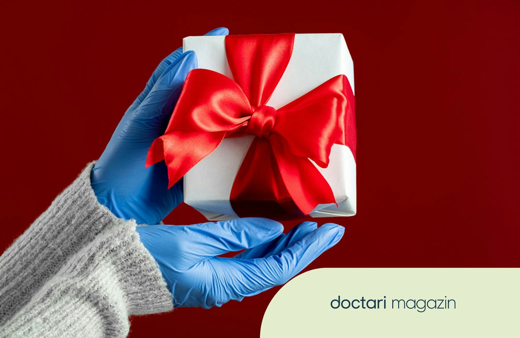 Zwei Hände in blauen Handschuhen halten ein Geschenk.