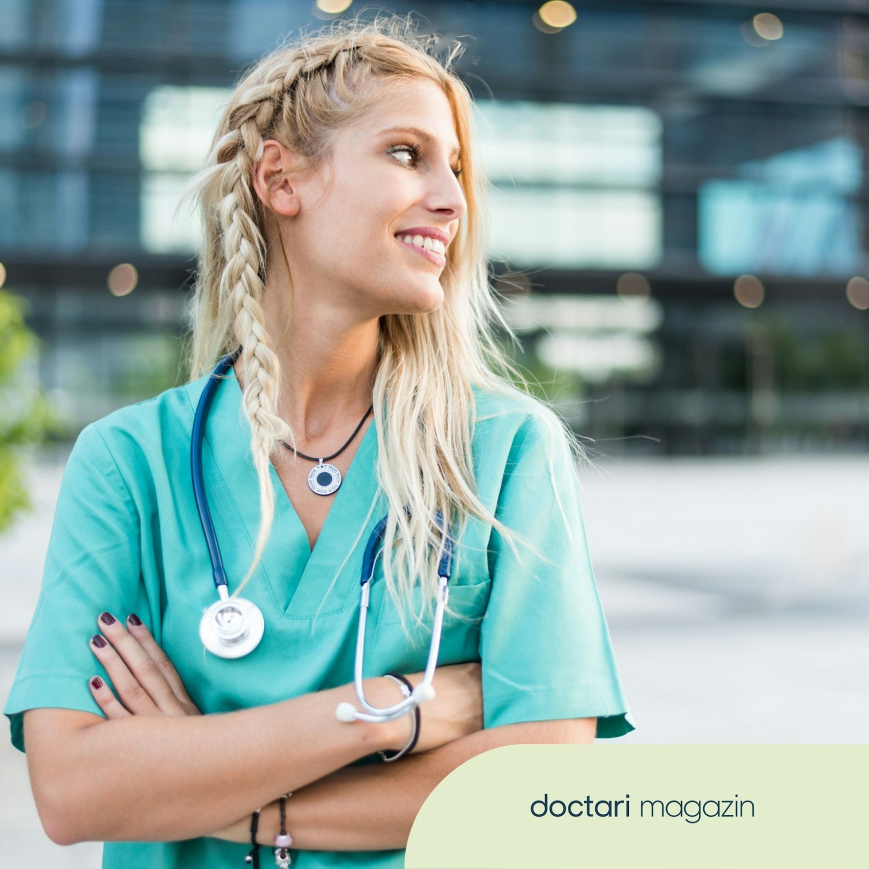 Junge Pflegerin im grünen Kittel und mit Stethoskop um den Hals.