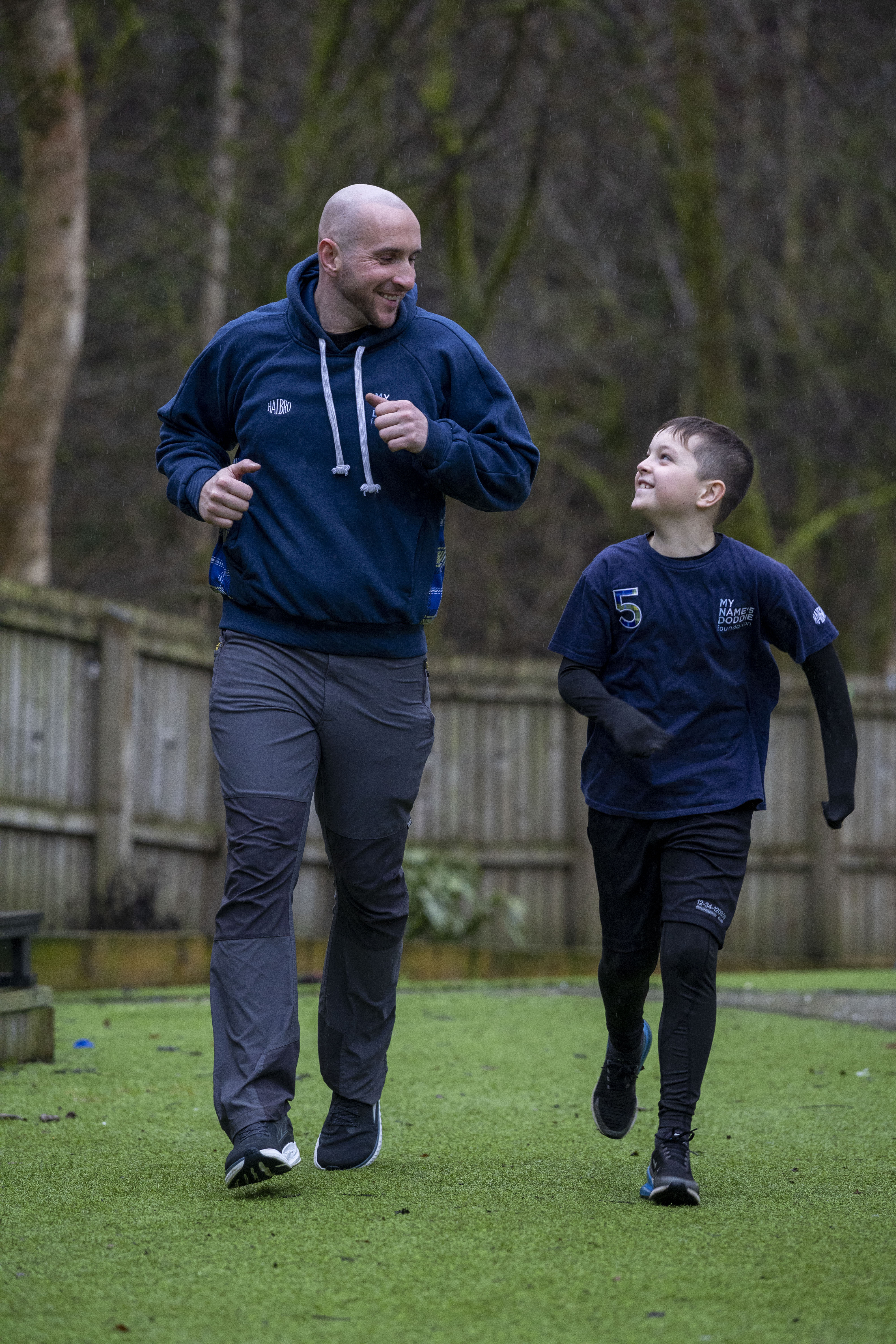 Harvey Dooher smiling and jogging alongside a child. 