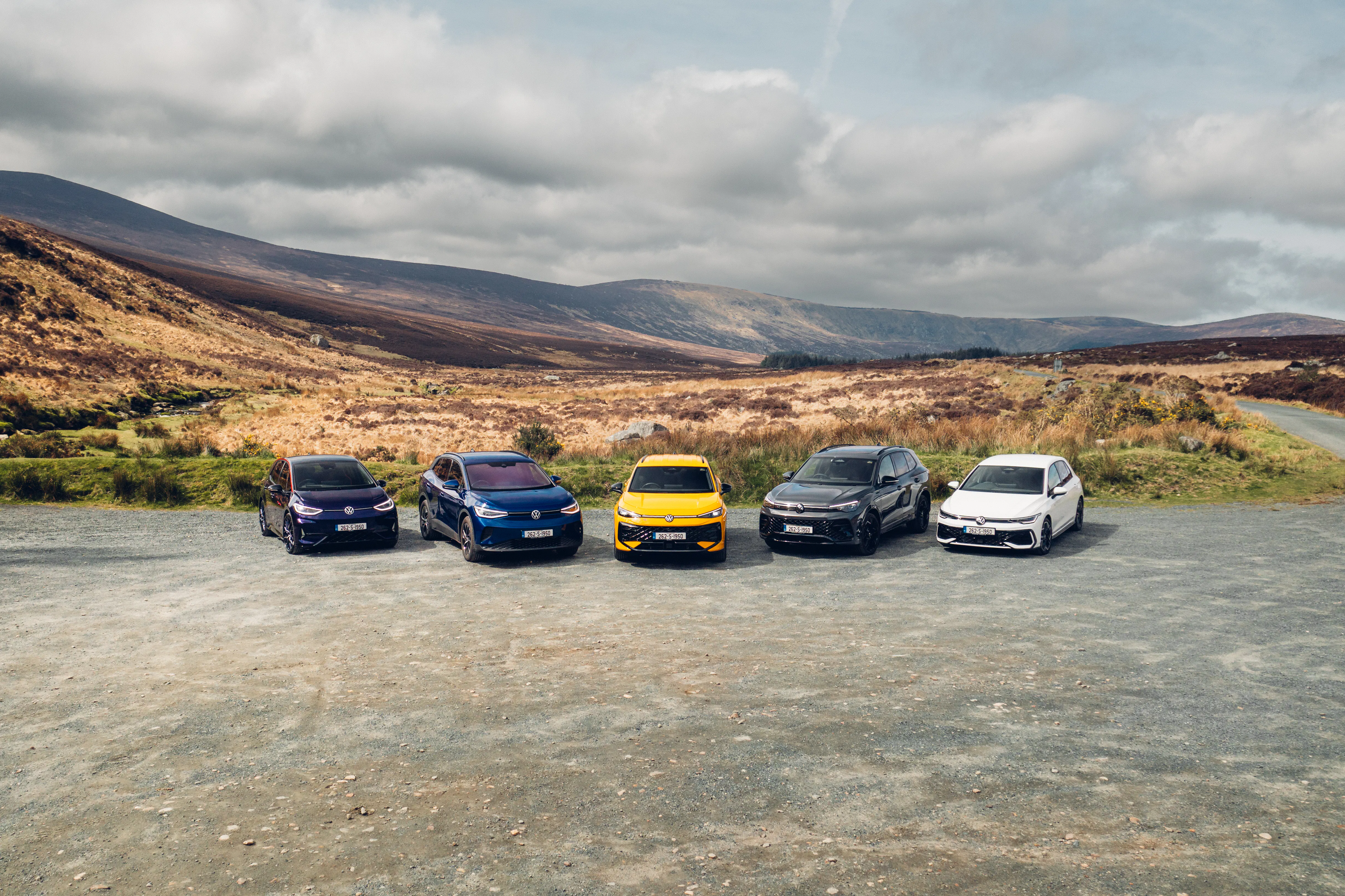 Line-up of Volkswagen passenger cars covered by the Volkswagen Ireland Scrappage Offer, parked outdoors against a hillside backdrop