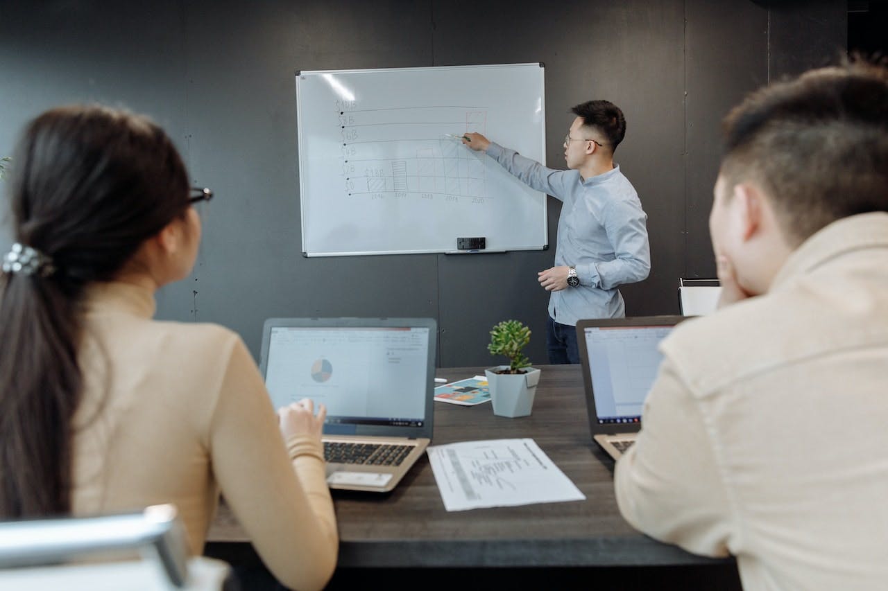 Person in meeting pointing at whiteboard