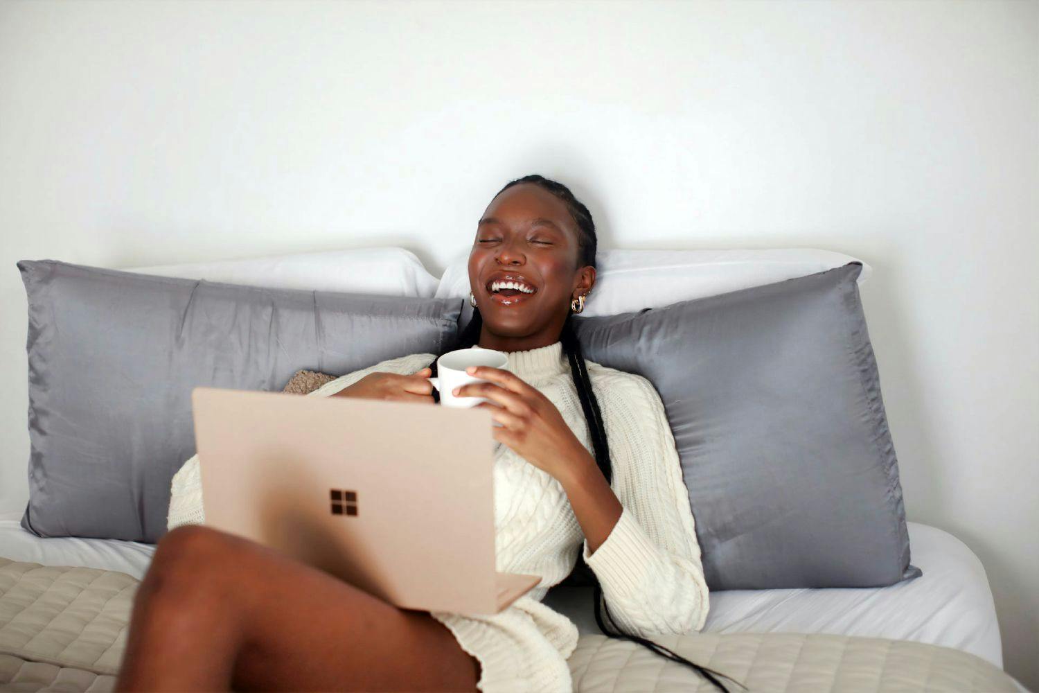 Women laughing on couch with laptop