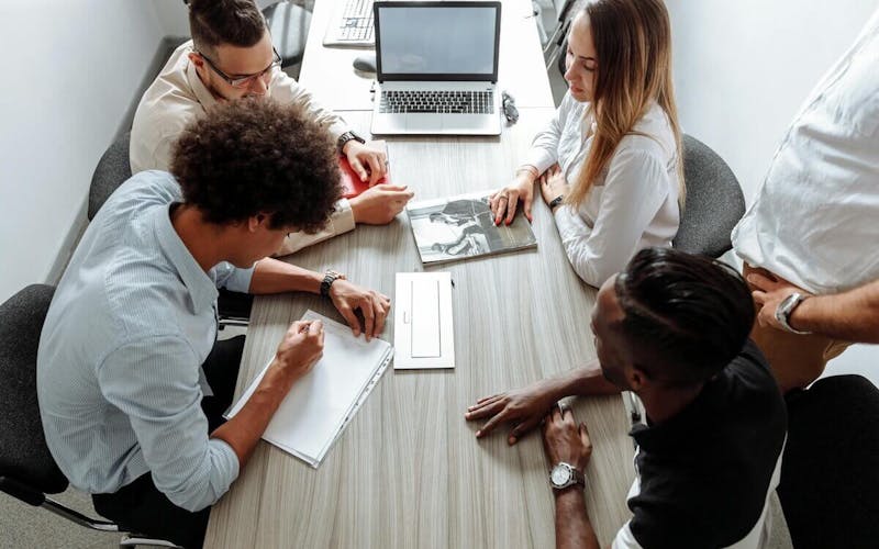 Vier Personen arbeiten gemeinsam an einem Tisch