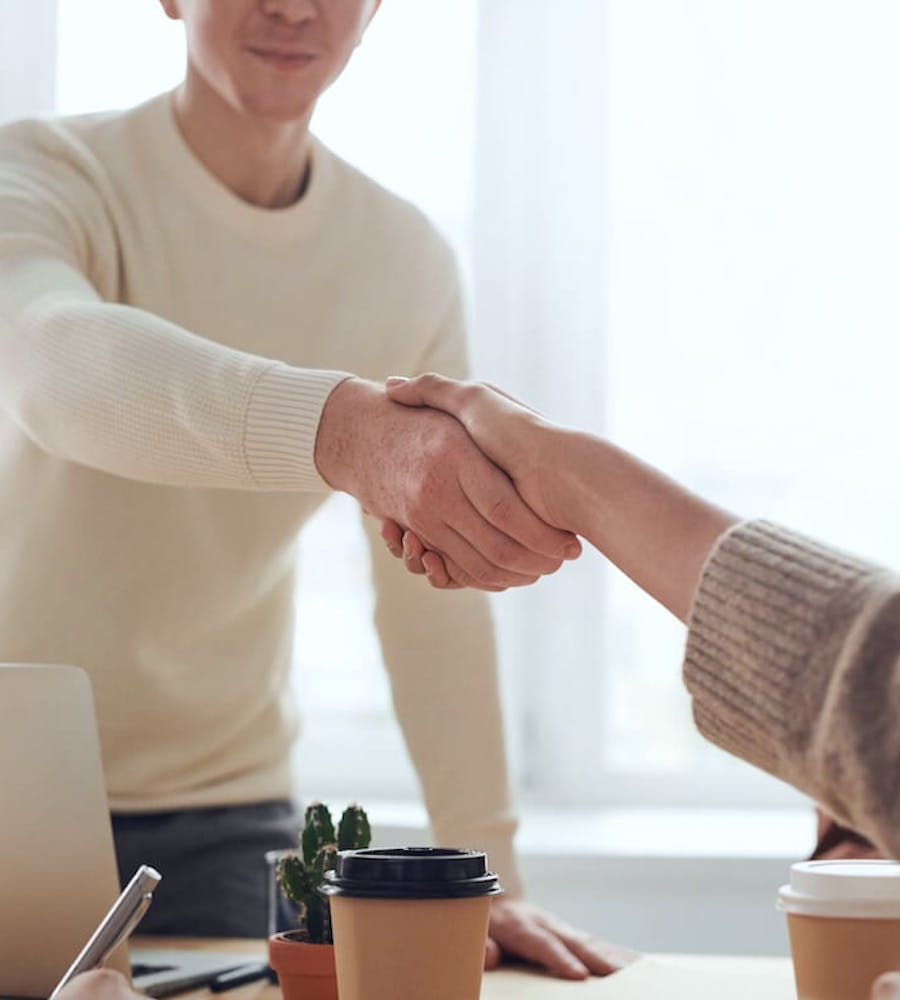 Zwei Personen geben sich am Schreibtisch die Hand