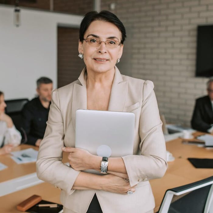 Eine Frau steht vor einem Besprechungstisch mit weiteren Personen