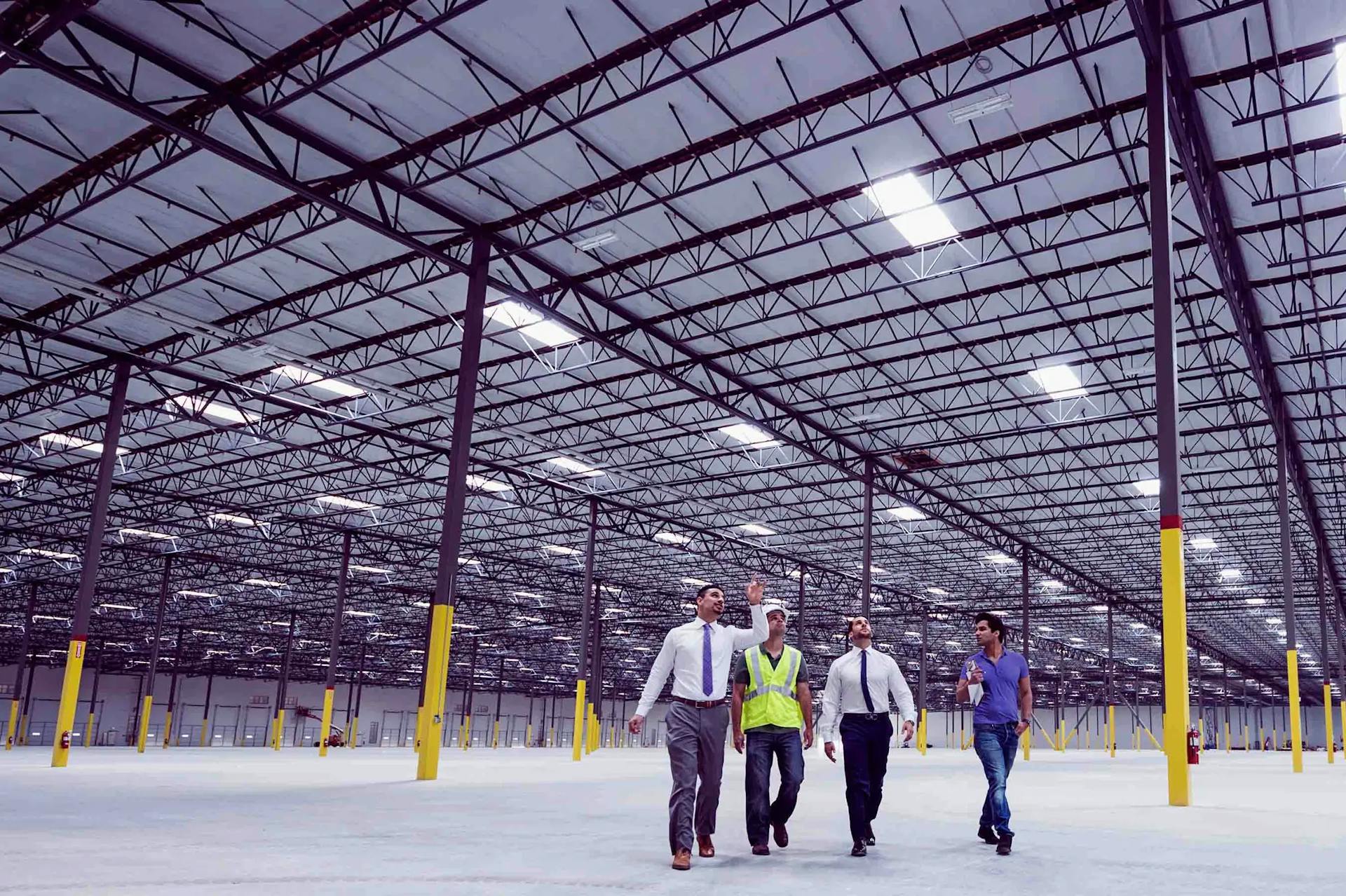 4 people in a warehouse pointing
