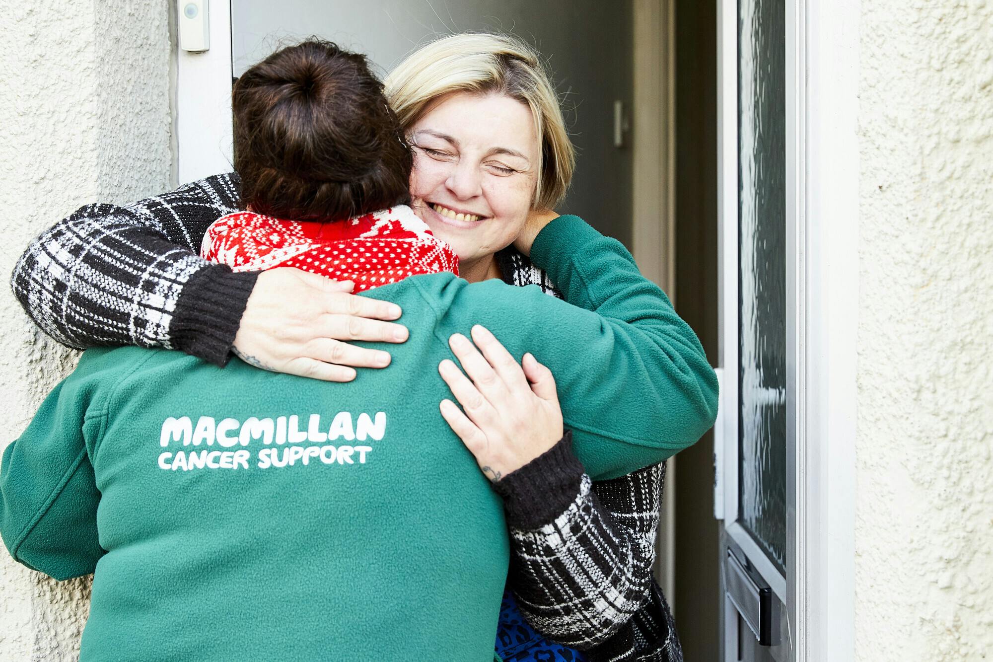 Macmillan fundraiser hugging woman at front door