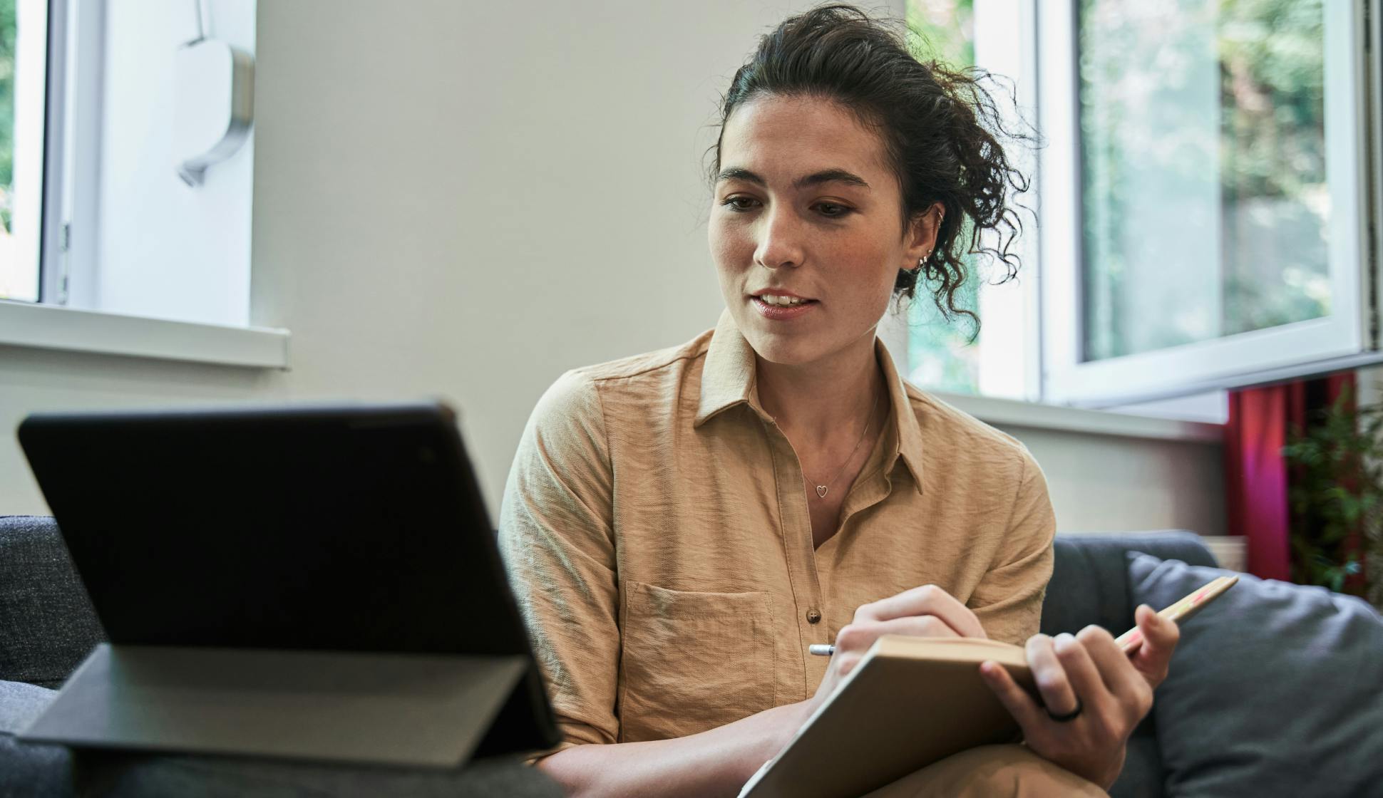 A mid age female therapist looking at her digital tablet while on a telemedicine session with a patient