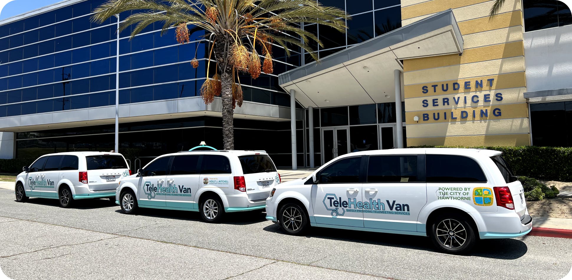Three TeleHealth Vans parked in front of a student services building