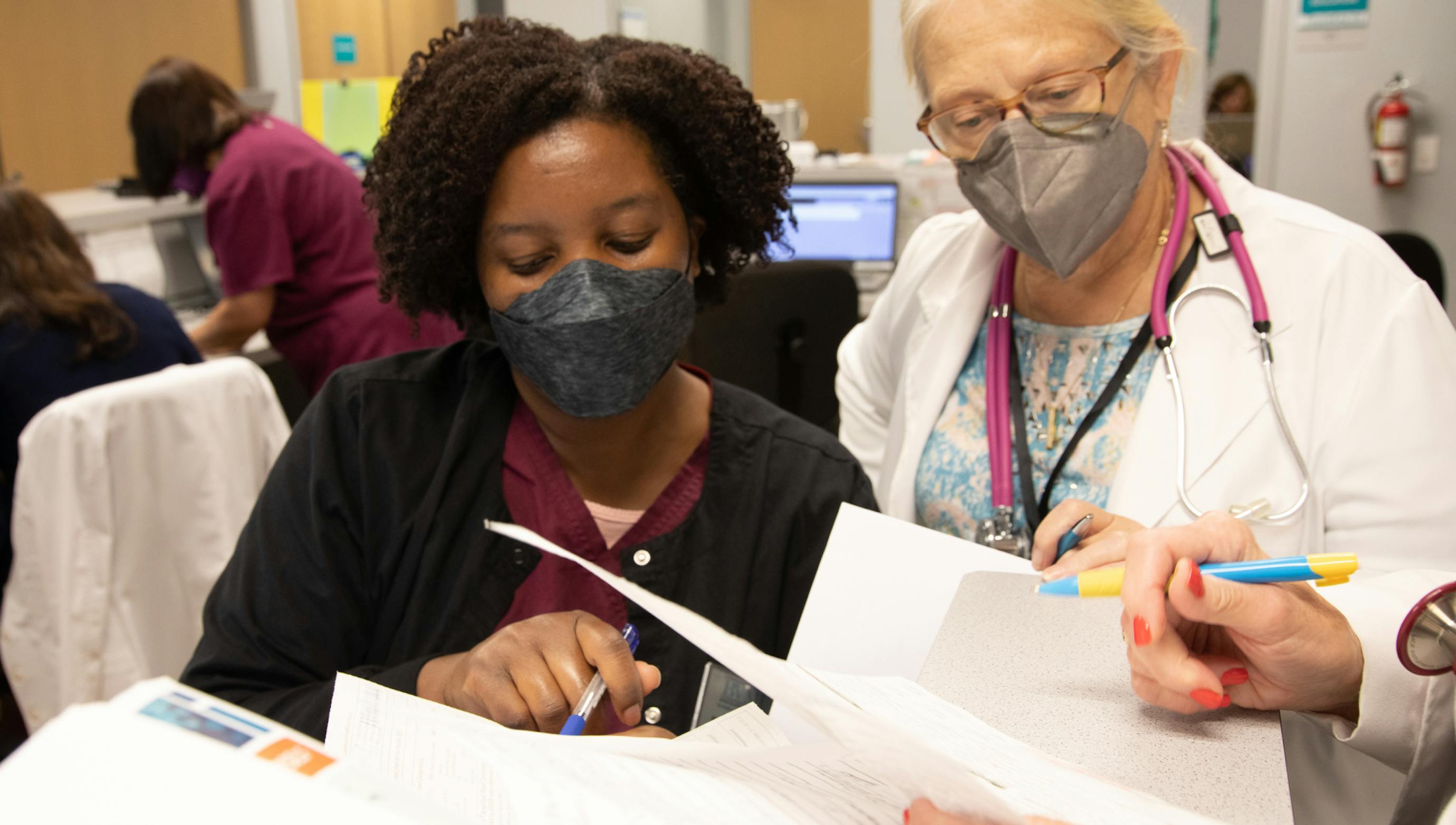 White physician and African American healthcare worker reviewing paperwork together