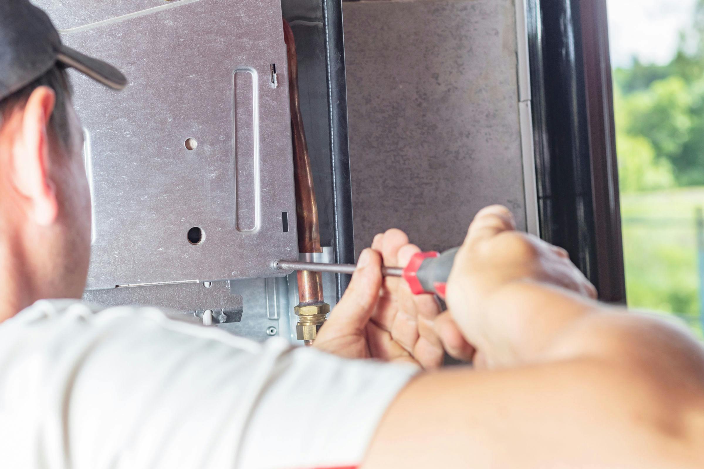 Close up of service tech undoing cover on boiler assembly