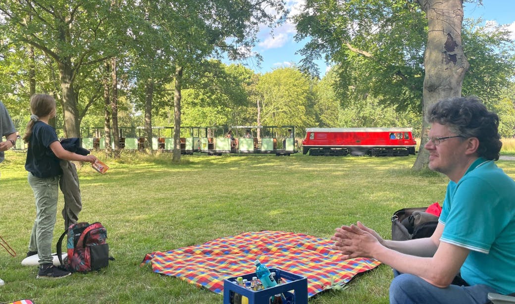 Gemeinsames Picknick im Dresdner Großen Garten mit der Parkbahn im Hintergrund
