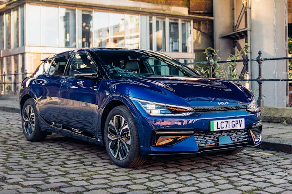 Blue Kia EV6 electric car on cobbled city street