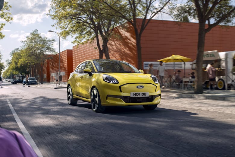 Ford Puma Gen e yellow electric car front profile with cafe in background