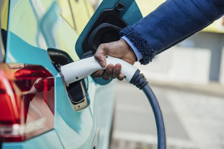 Close up of someone plugging in a light blue electric car to charge