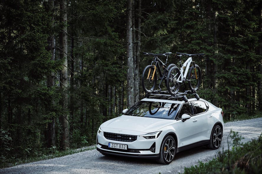 Polestar 2 with bike rack on roof driving through forrest
