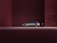 Volvo ES90 electric car side profile parked in front of a dark red background