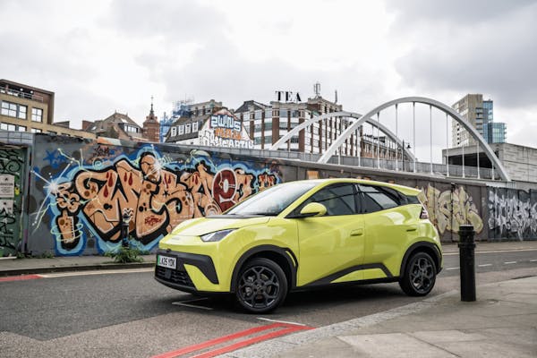 byd dolphin surf electric car in neon yellow with graffiti in background 