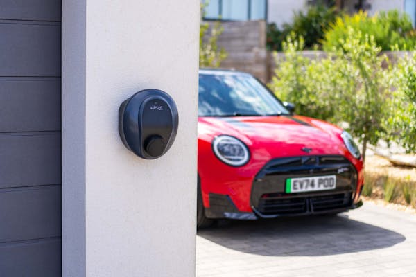 Red electric mini cooper ev parked on driveway next to garage with podpoint solo 3s charger
