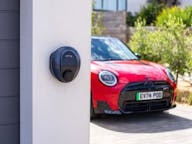 Red electric mini cooper ev parked on driveway next to garage with podpoint solo 3s charger