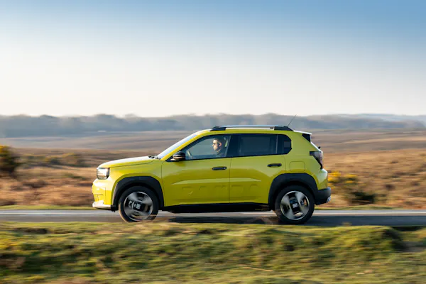 Fiat grande panda electric car in bright yellow. driving in british countryside