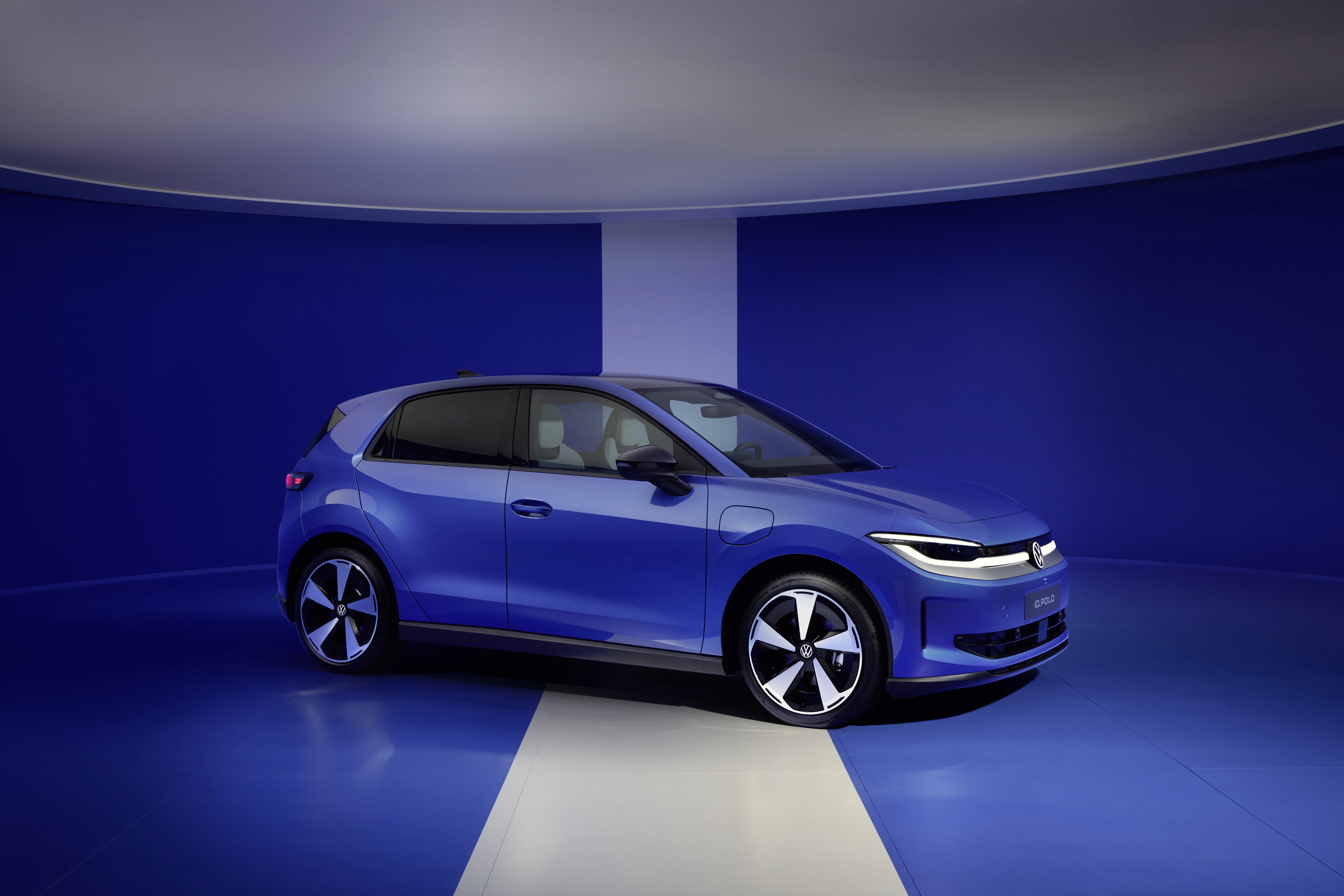 Volkswagen id polo electric car in bright blue front side view, with blue and white background