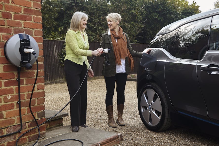 Two women stood in the driveway of a house charging a car