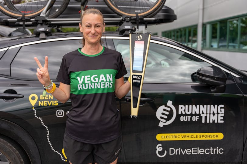 Victoria Hatch, Running Out of Time relay stage runner, with the all-electric Nissan Ariya support team vehicle sponsored by DriveElectric. 